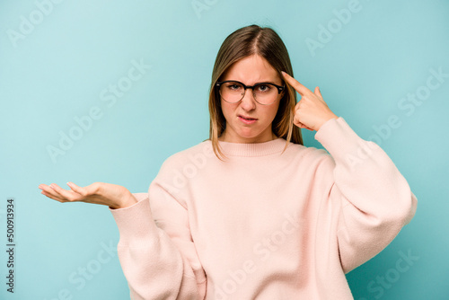 Young caucasian woman isolated on blue background showing a disappointment gesture with forefinger.