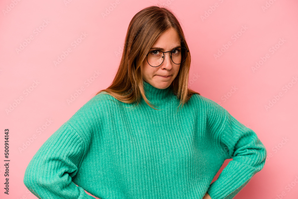 Young caucasian woman isolated on pink background frowning face in displeasure, keeps arms folded. Young caucasian woman isolated on pink background frowning face in displeasure, keeps arms folded.