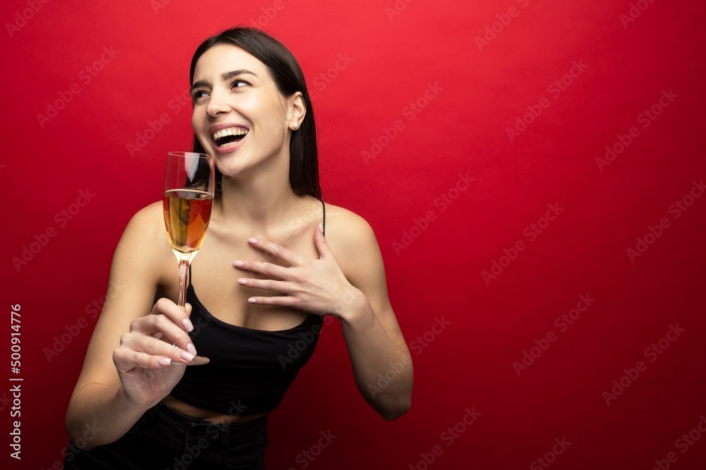 Smiling brunette with a glass of champagne on a red background Smiling brunette with a glass of champagne on a red background