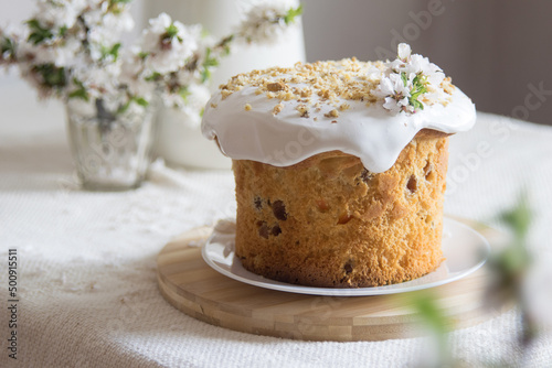 Traditional easter cake or sweet bread, apple brahces in bloom on white plate on light linen tablecloth. Side view, selective focus. Easter treat, holiday symbol