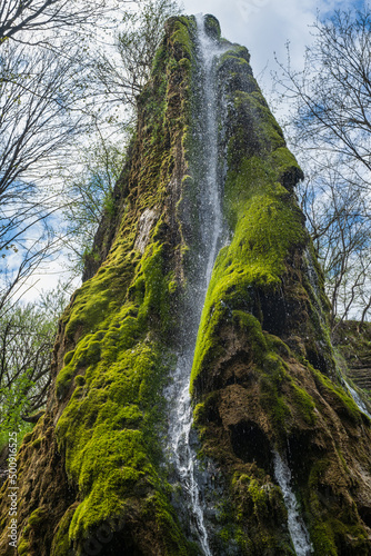 Amazing spring picturesque waterfall on steep rocky cliff. The former Orlovsky estates park, Maliivtsi, Khmelnytsky region, Ukraine.