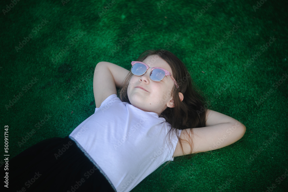 dziewczynka leży na trawie i patrzy w niebo - obrazy, fototapety, plakaty 