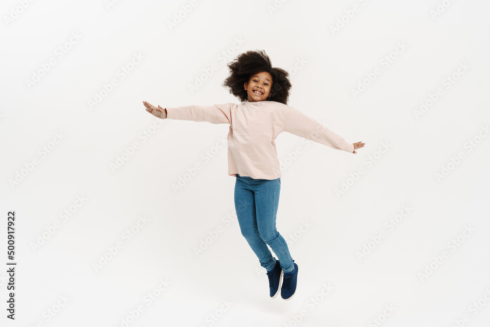 Black preteen girl with curly hair jumping and laughing