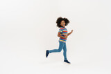 Black preteen girl with curly hair laughing while running