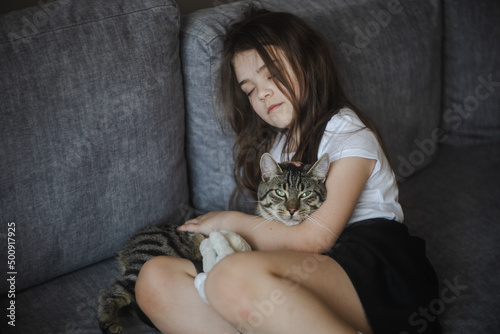 Młoda dziewczynka odpoczywająca z kotem na sofie