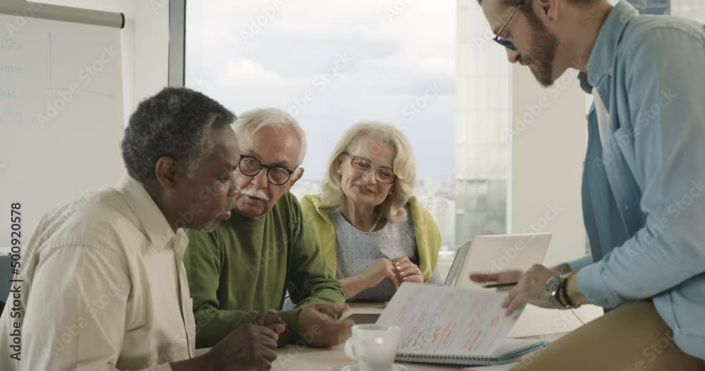 A group of multicultural senior students is discussing a programming project with an educator in the classroom. A group of multicultural senior students is discussing a programming project with an educator in the classroom.