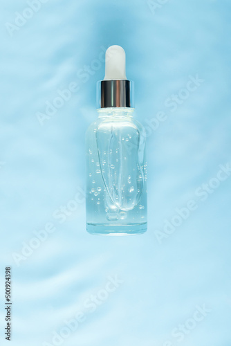 Serum glass bottle on water with drops Concept of moisturizing cosmetics with natural marine collagen. Skin care, anti-aging