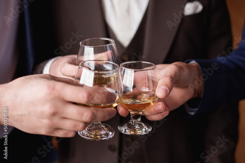 Groom with bestmen drinks whiskey from glasses. Closeup © rostyslav84