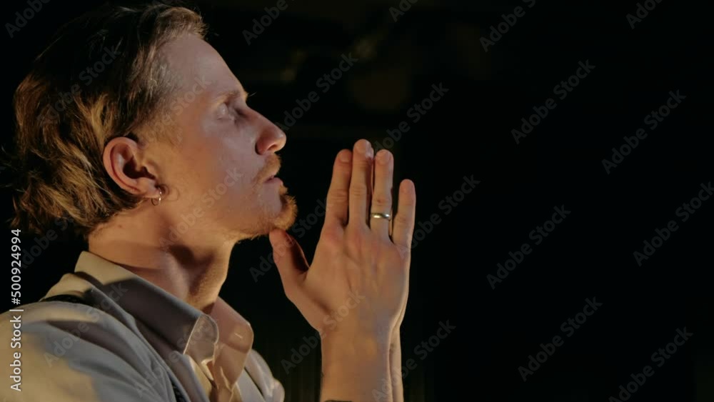 Hope or confession - concept. Artist Man with curly hair performance emotional pray raising his hands up in yellow rays of the sun on a black background. Hope or confession - concept. Artist Man with curly hair performance emotional pray raising his hands up in yellow rays of the sun on a black background.