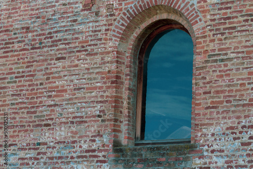 Low angle view of an old stone window reflcting sky and clouds. Copy space. photo