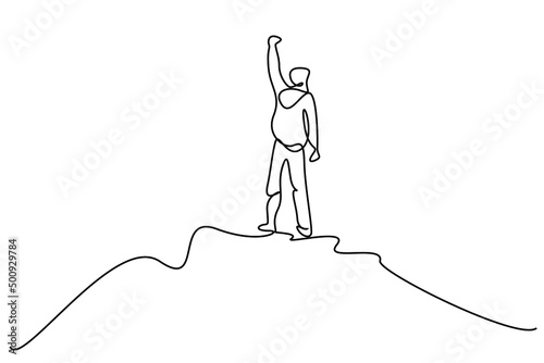 a person climbing to the top of a mountain top raises his arms in the air