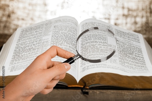 A magnifying glass in hand with open bible book. photo