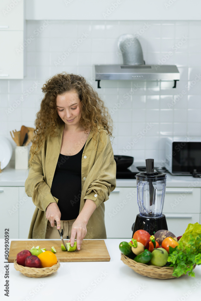 woman stand, cut green apple, make diet fruit juice, looking at knife in kitchen with copy space. beautiful caucasian pregnant woman cooking healthy diet fruit or food in kitchen woman stand, cut green apple, make diet fruit juice, looking at knife in kitchen with copy space. beautiful caucasian pregnant woman cooking healthy diet fruit or food in kitchen