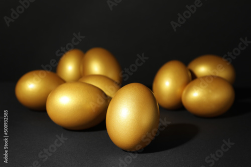 Many shiny golden eggs on black background