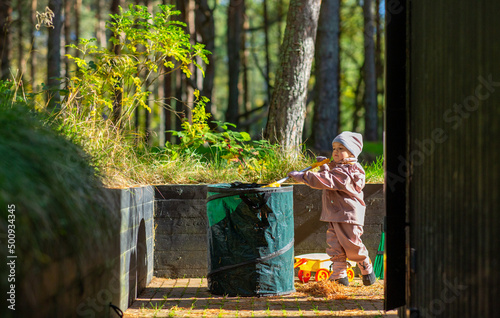childhood, leisure and autumn season concept - happy little baby girl helping clean up backyard