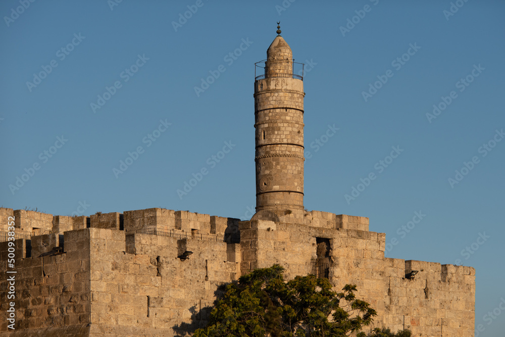 Afternoon view of the landmark, stone Tower of David minaret as golden sunlight strikes the ancient walls of the Old City of Jerusalem.