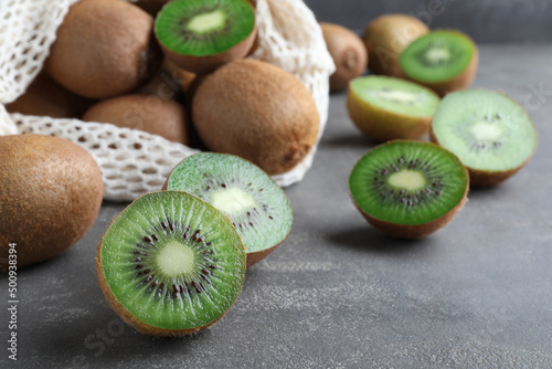 Cut and whole fresh ripe kiwis on grey table, closeup