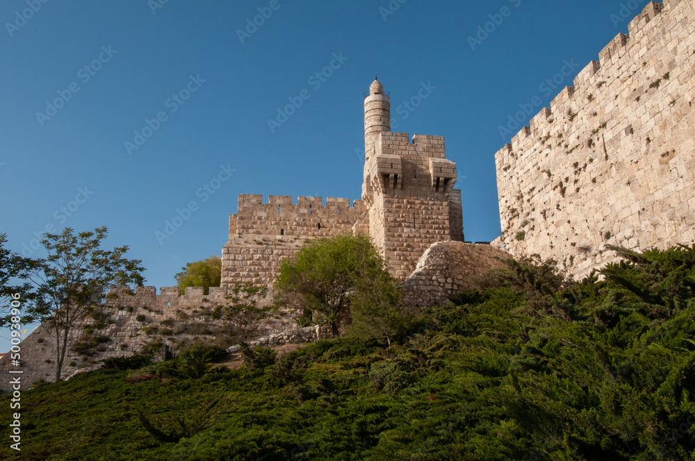 View of the landmark, stone Tower of David and the surrounding walls and greenery of the Old City of Jerusalem.