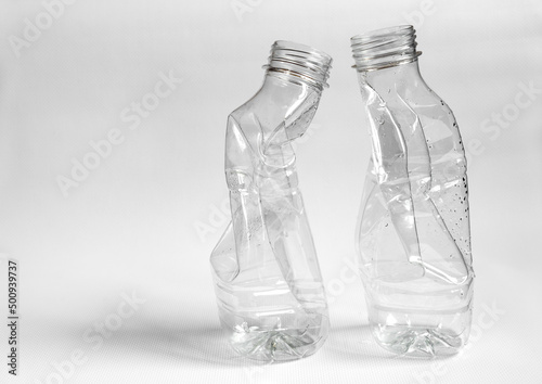 Side view of two crushed plastic bottles prepared for recycle on a light background. Waste sorting and plastic recycle concept
