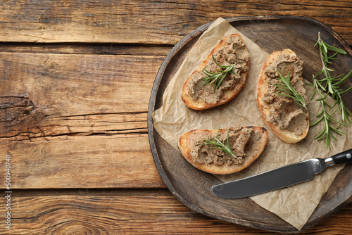 Slices of bread with delicious pate and rosemary on wooden table, top view. Space for text