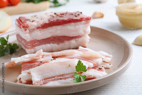 Tasty salt pork with parsley on white wooden table, closeup