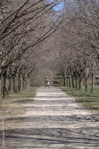 Gravel park path leading up ti a stone statue