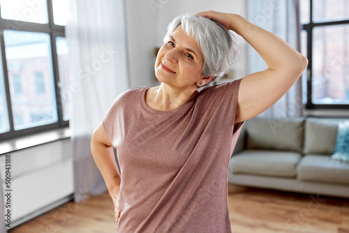 sport, fitness and healthy lifestyle concept - close up of smiling senior woman exercising on mat and stretching neck at home