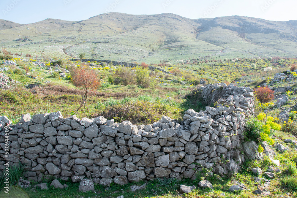 Ancient stone wall in the field under the mountain