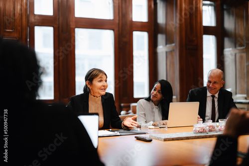 Smiling businesswoman discussing strategy with colleagues in board room at law office photo