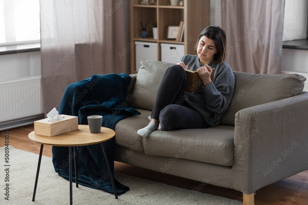 people, leisure and depression concept - sad woman with diary sitting on sofa at home people, leisure and depression concept - sad woman with diary sitting on sofa at home