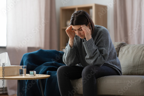 mental health, psychological problem and depression concept - stressed woman with sedative medicine or painkiller on table having headache at home photo