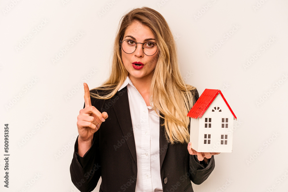 Young business caucasian woman holding a toy house isolated on white background having some great idea, concept of creativity. Young business caucasian woman holding a toy house isolated on white background having some great idea, concept of creativity.