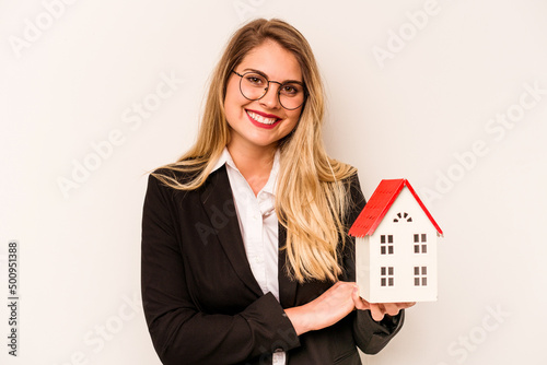 Young business caucasian woman holding a toy house isolated on white background laughing and having fun.
