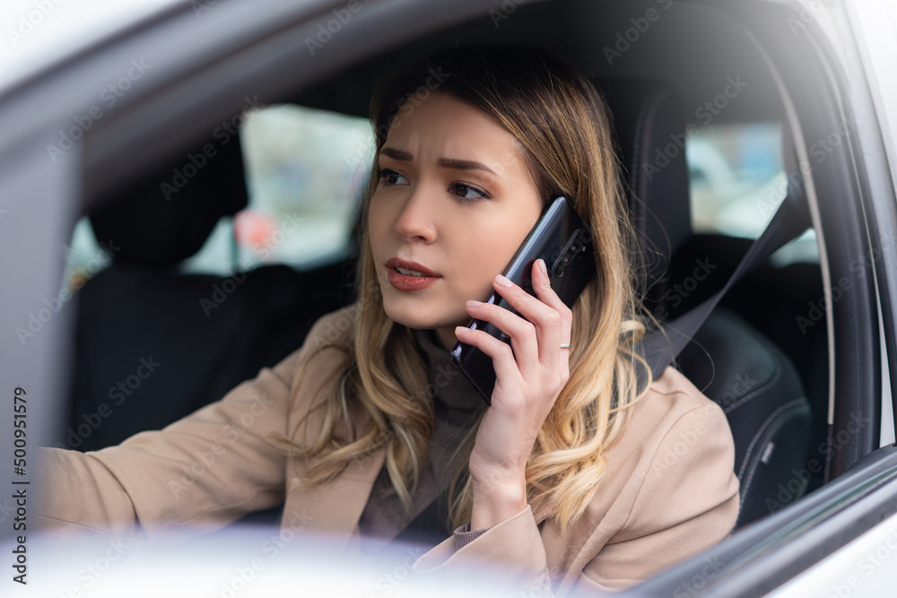 Businesswoman driving car and talking on cell phone concentrating on the road