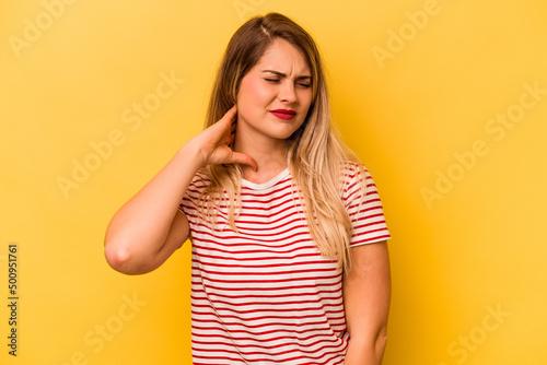 Young caucasian woman isolated on yellow background having a neck pain due to stress, massaging and touching it with hand.