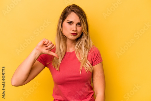 Young caucasian woman isolated on yellow background showing a dislike gesture, thumbs down. Disagreement concept.
