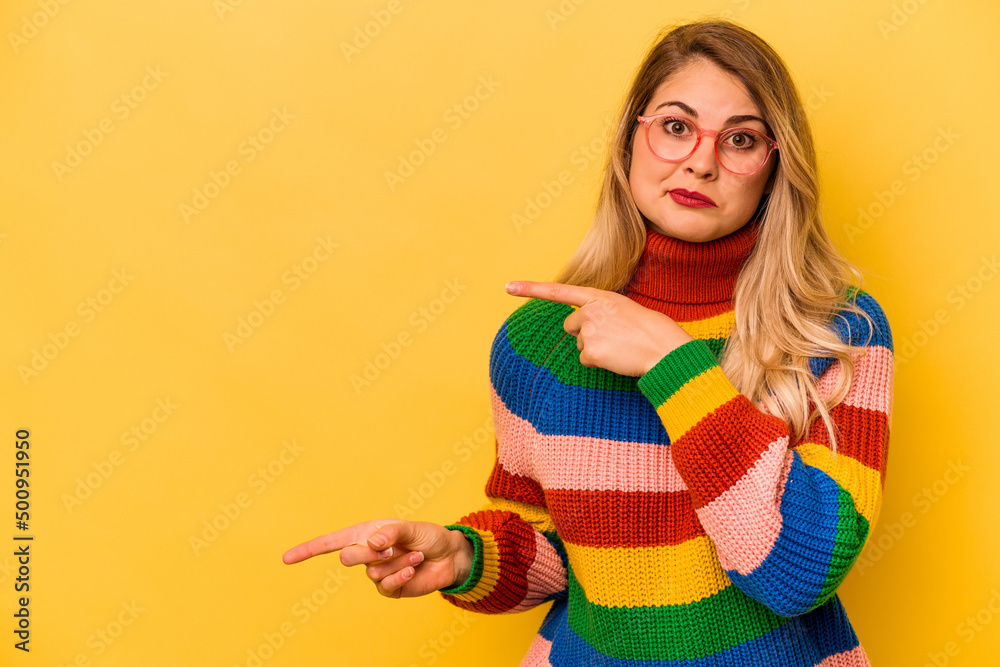 Young caucasian woman isolated on yellow background shocked pointing with index fingers to a copy space. Young caucasian woman isolated on yellow background shocked pointing with index fingers to a copy space.