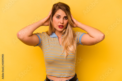Young caucasian woman isolated on yellow background covering ears with hands trying not to hear too loud sound.