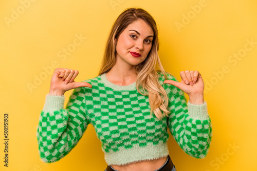 Young caucasian woman isolated on yellow background feels proud and self confident, example to follow. © Asier