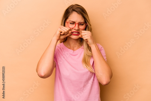 Young caucasian woman isolated on beige background whining and crying disconsolately.