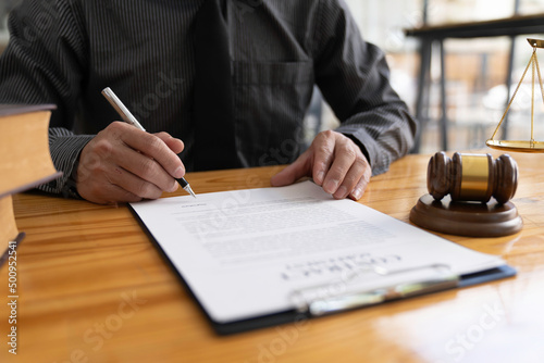 Lawyer man holding pen with contract or agreement document to the customer for signing in courtroom legal, Sign a contract business. © crizzystudio