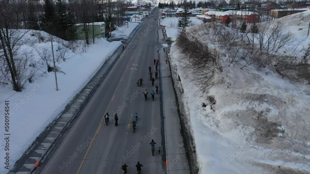 more than twenty people on fat bikes enjoying a ride along road during event for biking in Alaska on a snowy April evening more than twenty people on fat bikes enjoying a ride along road during event for biking in Alaska on a snowy April evening
