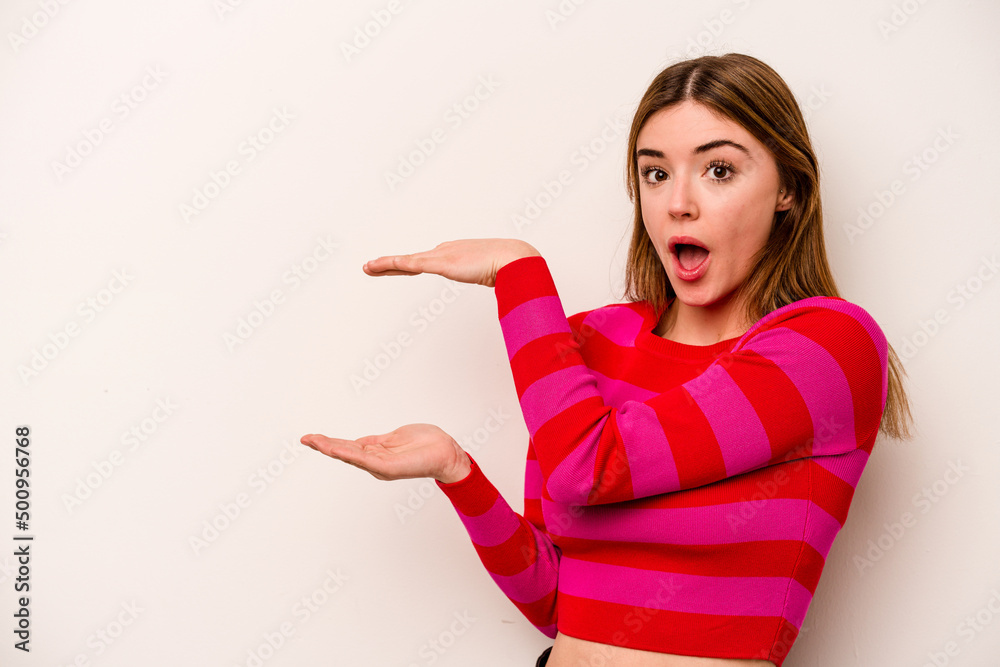 Young caucasian woman isolated on white background shocked and amazed holding a copy space between hands. Young caucasian woman isolated on white background shocked and amazed holding a copy space between hands.