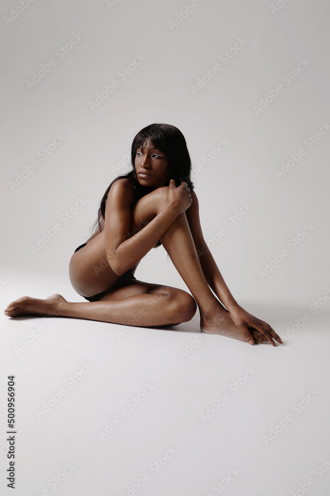 Beautiful African woman with long dark hair posing indoor sitting on the floor. 