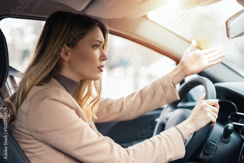 Angry young sitting woman pissed off by drivers in front of her and gesturing with hands