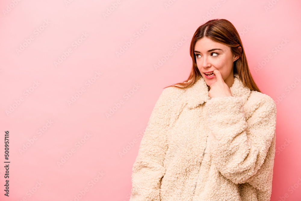 Young caucasian woman isolated on pink background relaxed thinking about something looking at a copy space. Young caucasian woman isolated on pink background relaxed thinking about something looking at a copy space.