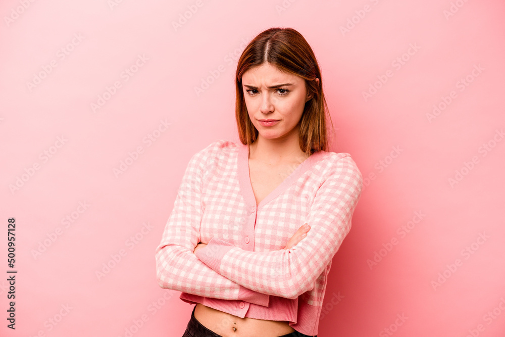 Young caucasian woman isolated on pink background frowning face in displeasure, keeps arms folded. Young caucasian woman isolated on pink background frowning face in displeasure, keeps arms folded.