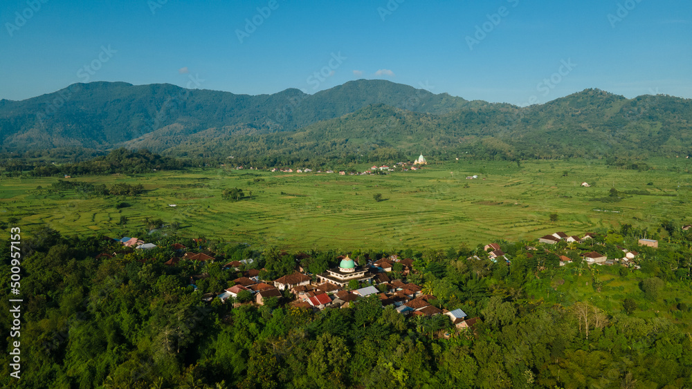 Aerial view of terraced rice fields, green farm fields in rural or rural areas of Lombok. Mountain hill valley at sunrise in Asia. Natural scenery background.