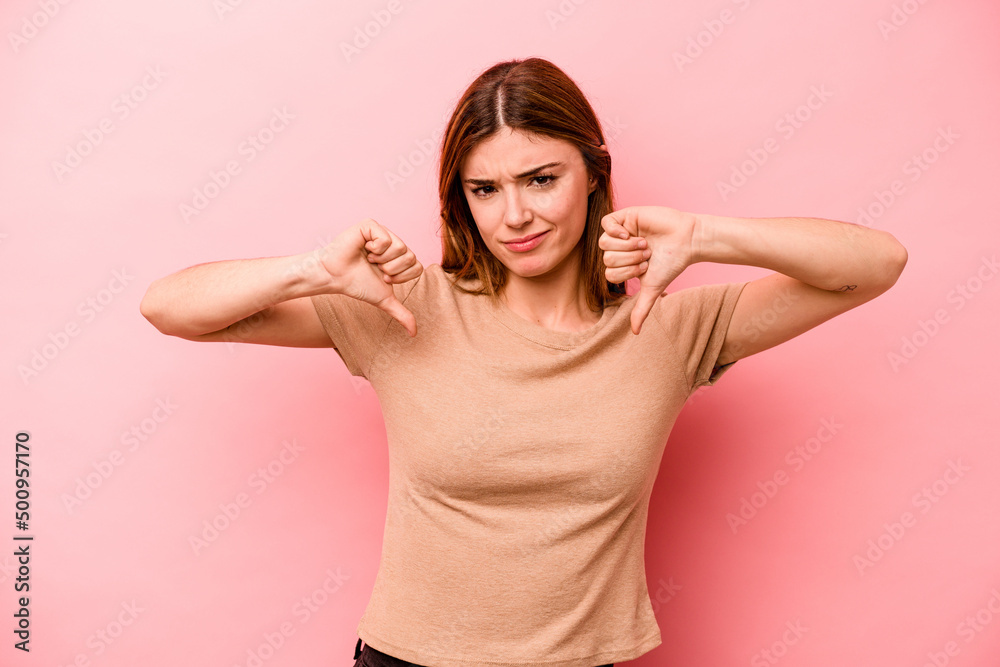 Fototapeta premium Young caucasian woman isolated on pink background showing thumb down, disappointment concept.