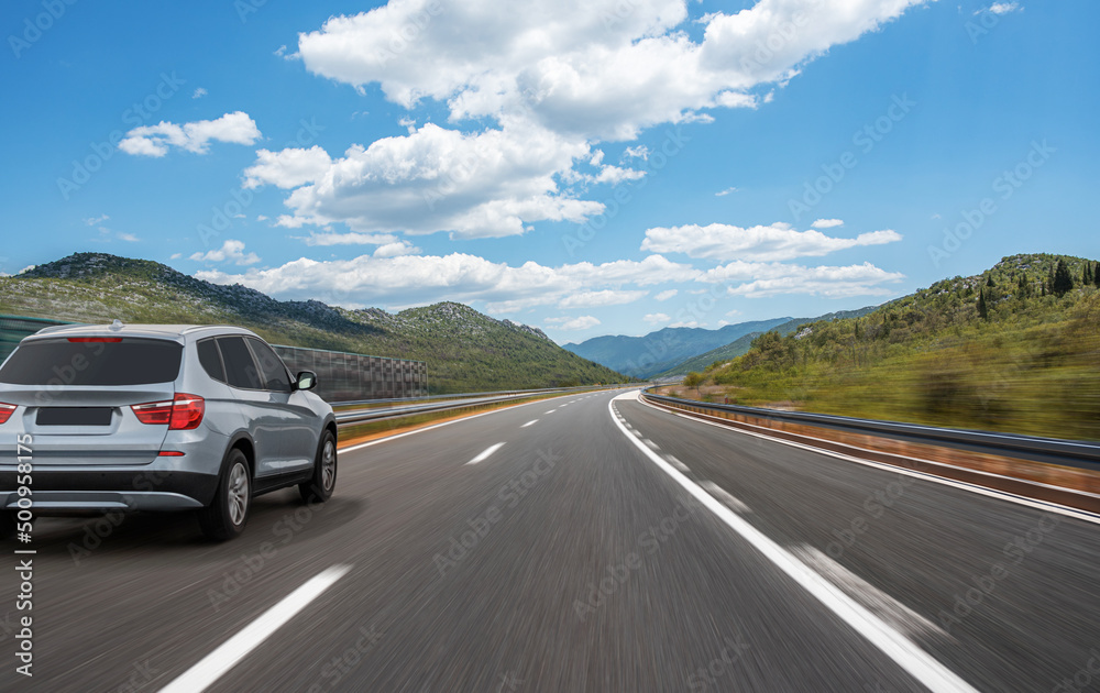 Fototapeta premium Car on a scenic road. Car on the road surrounded by a magnificent natural landscape.